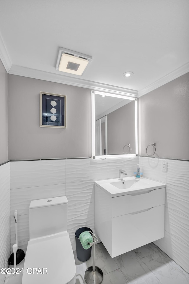 bathroom with tile walls, vanity, ornamental molding, and toilet