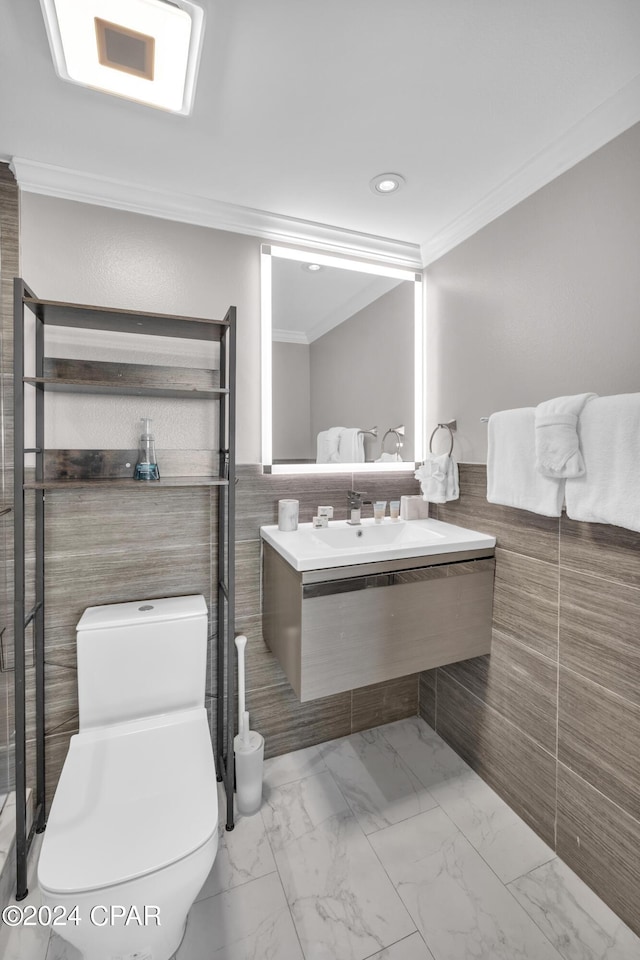 bathroom with tile walls, vanity, crown molding, and toilet