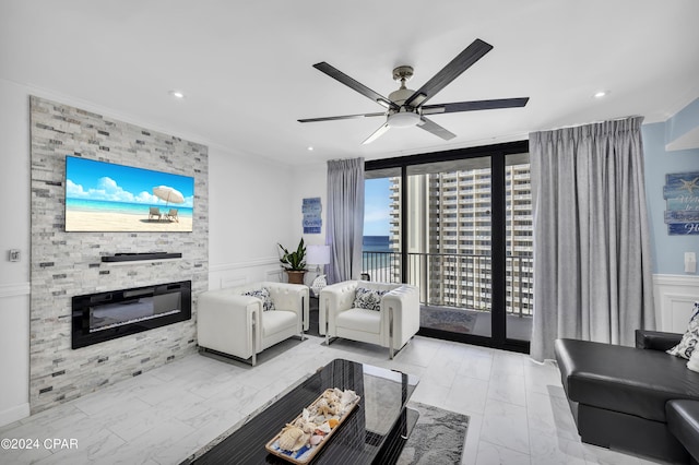 living room featuring ornamental molding, a stone fireplace, and ceiling fan