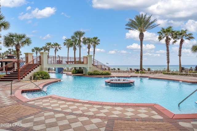 view of pool featuring a patio, a water view, and cooling unit