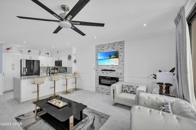 living room featuring sink, a fireplace, and ceiling fan