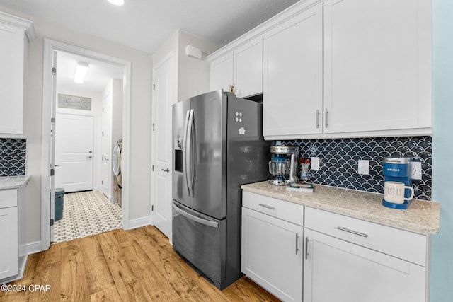 kitchen with white cabinets, light stone counters, light wood-type flooring, backsplash, and stainless steel fridge with ice dispenser