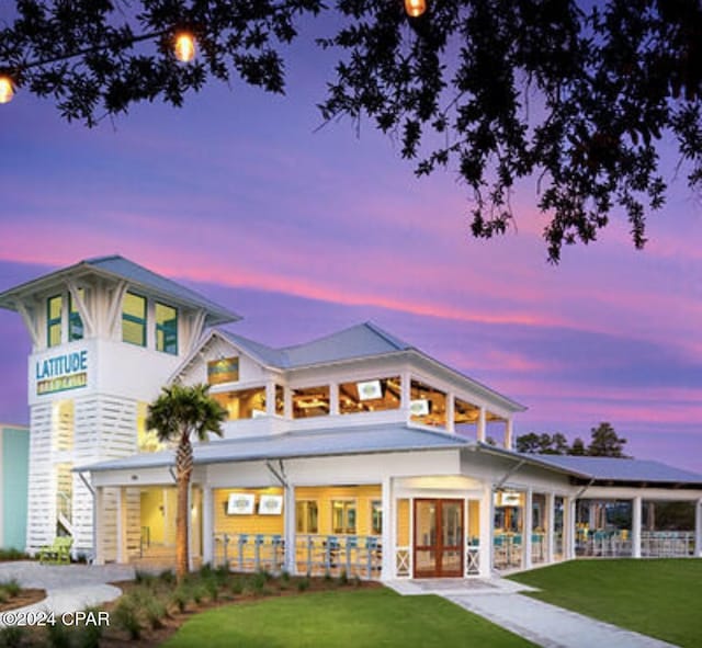 back house at dusk featuring a yard and a balcony