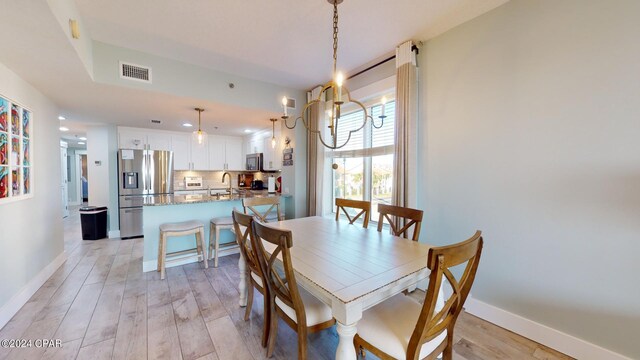 dining area with light hardwood / wood-style floors, a chandelier, and sink