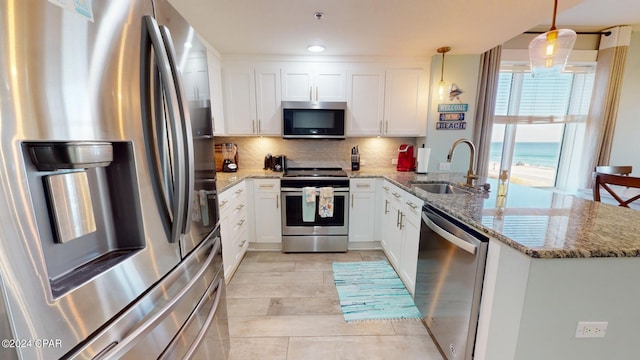 kitchen with tasteful backsplash, a peninsula, stainless steel appliances, white cabinetry, and a sink