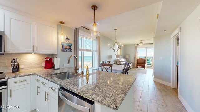 kitchen with stainless steel appliances, ceiling fan with notable chandelier, sink, white cabinetry, and light hardwood / wood-style floors