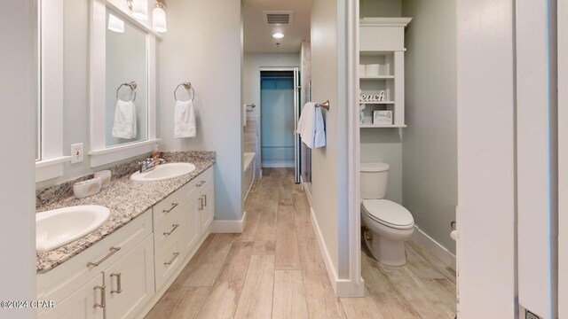 bathroom featuring toilet, a tub, vanity, and wood-type flooring