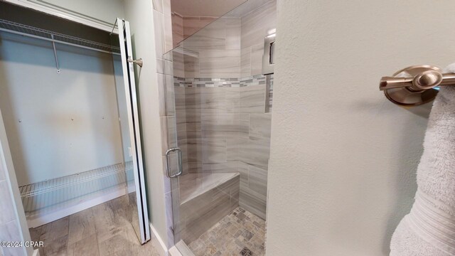 bathroom with hardwood / wood-style flooring and a shower with shower door