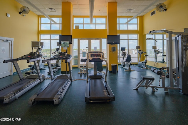 gym with a high ceiling, a paneled ceiling, and visible vents