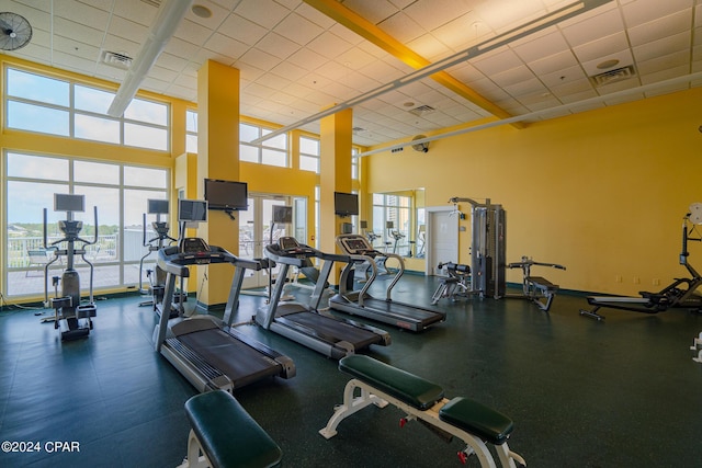 exercise room featuring a drop ceiling, visible vents, and a towering ceiling