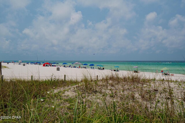 surrounding community featuring a yard, a water view, and a beach view