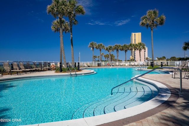 pool with a patio area, a city view, and fence