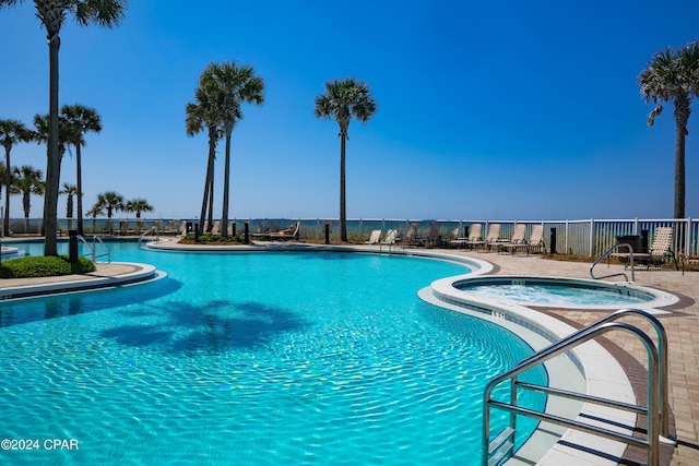 pool with a patio area, a community hot tub, and fence