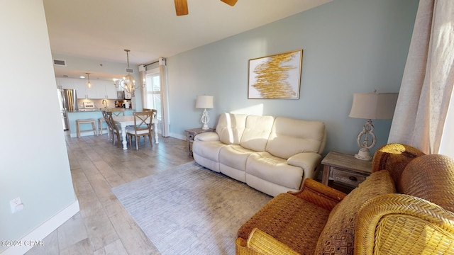 living area featuring light wood-type flooring, baseboards, visible vents, and a ceiling fan