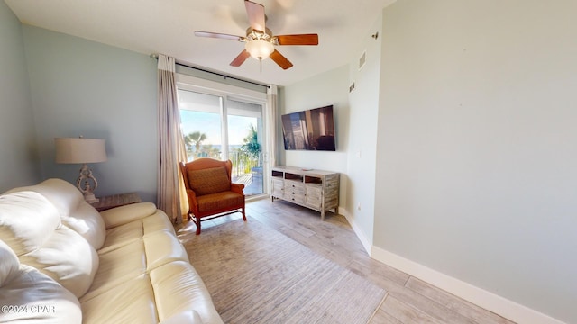 living room with visible vents, baseboards, light wood-type flooring, and a ceiling fan