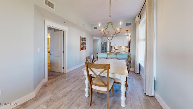 dining space featuring light hardwood / wood-style floors and a notable chandelier