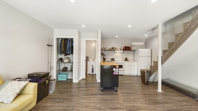 kitchen featuring an AC wall unit, white cabinetry, dark wood-type flooring, and white appliances