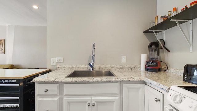 kitchen with light stone countertops, sink, white cabinets, and electric range