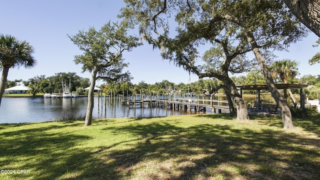 view of dock with a yard and a water view