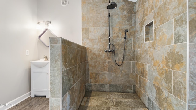 bathroom with hardwood / wood-style floors, vanity, and a tile shower