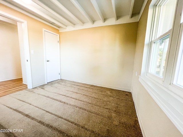 unfurnished bedroom featuring carpet flooring and beam ceiling