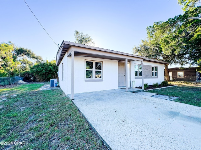 single story home featuring a patio area, a front lawn, and central AC unit