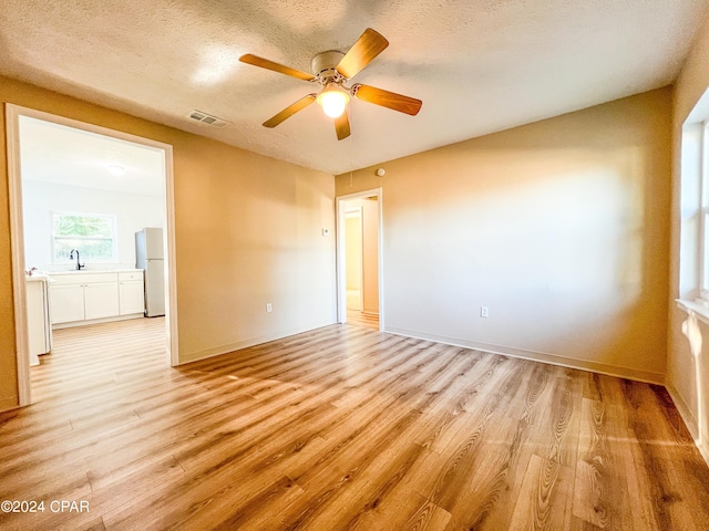 spare room with ceiling fan, sink, a textured ceiling, and light hardwood / wood-style flooring