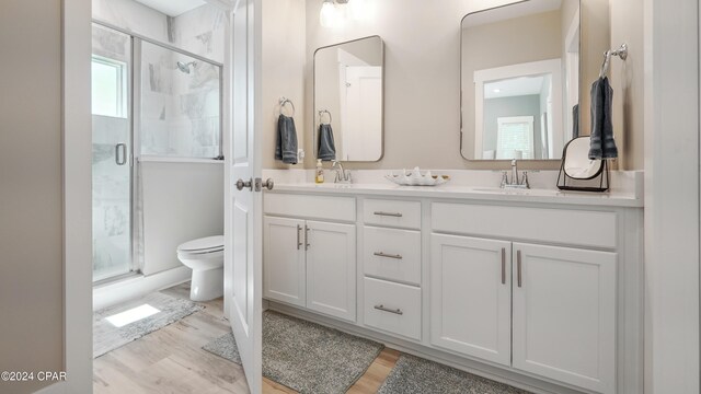 bathroom featuring hardwood / wood-style floors, vanity, a shower with door, and toilet