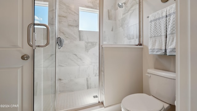 bathroom featuring toilet and a shower with door