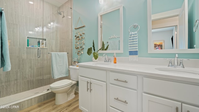 bathroom featuring wood-type flooring, vanity, toilet, and a shower with shower door