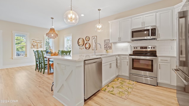 kitchen with white cabinetry, sink, stainless steel appliances, and decorative light fixtures