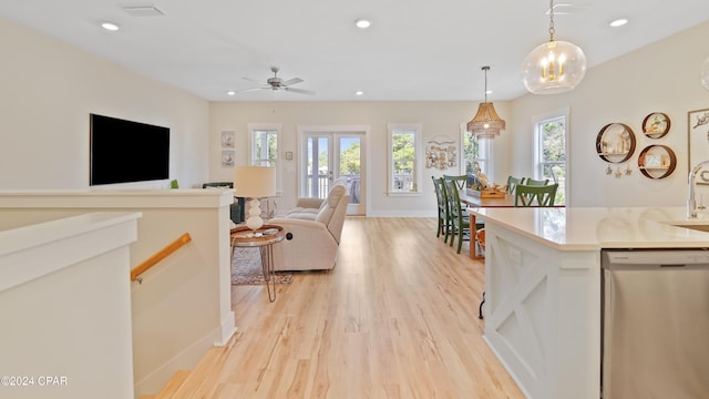 kitchen with plenty of natural light, stainless steel dishwasher, decorative light fixtures, and light wood-type flooring