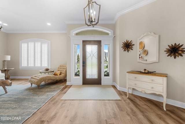 entrance foyer with crown molding, baseboards, wood finished floors, and a notable chandelier