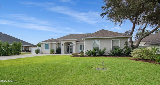 view of front of property with concrete driveway, a front yard, and stucco siding