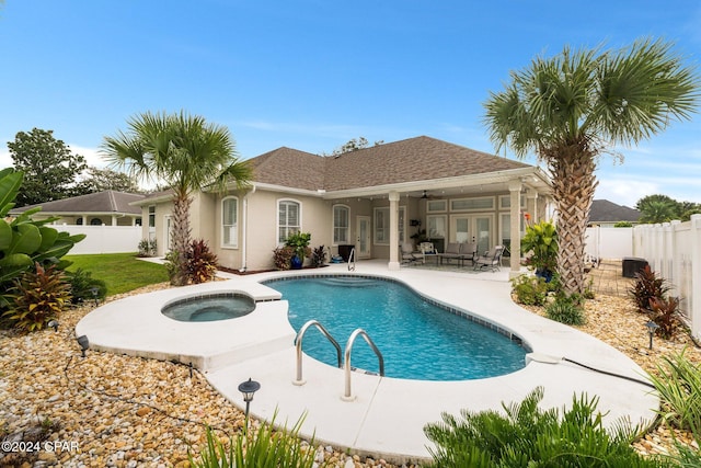 rear view of house featuring an in ground hot tub, a patio, a fenced backyard, and stucco siding