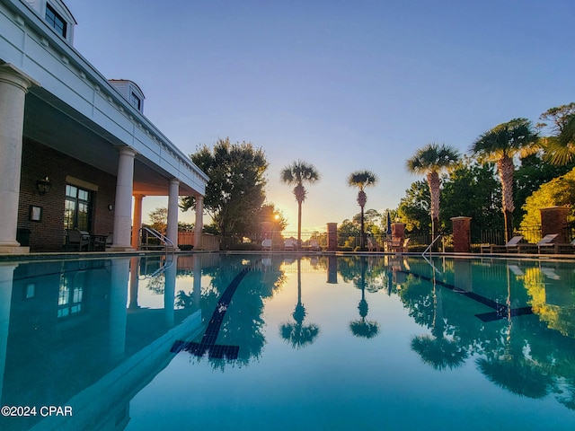 pool at dusk featuring a water view