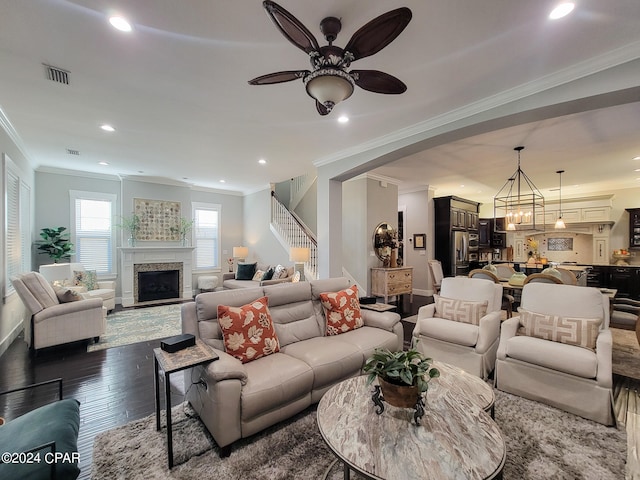 living room featuring wood-type flooring, ornamental molding, and ceiling fan with notable chandelier