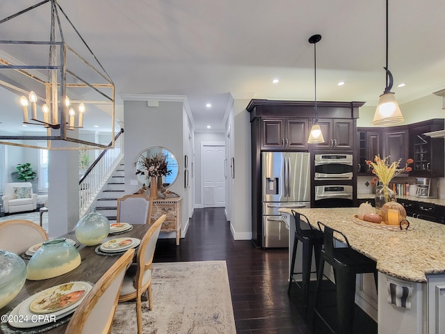 kitchen featuring ornamental molding, dark wood-type flooring, hanging light fixtures, and stainless steel appliances