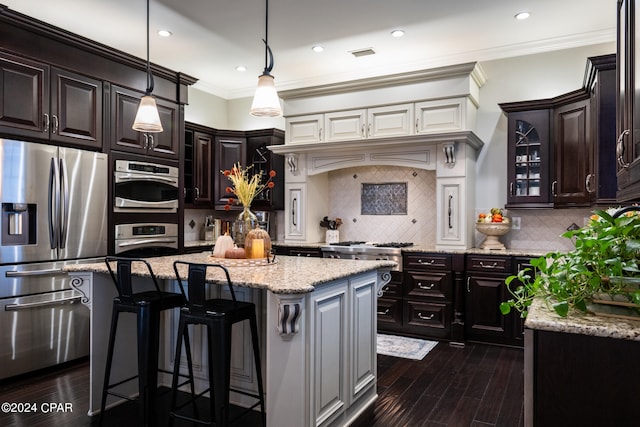 kitchen featuring appliances with stainless steel finishes, a center island, dark brown cabinetry, and tasteful backsplash