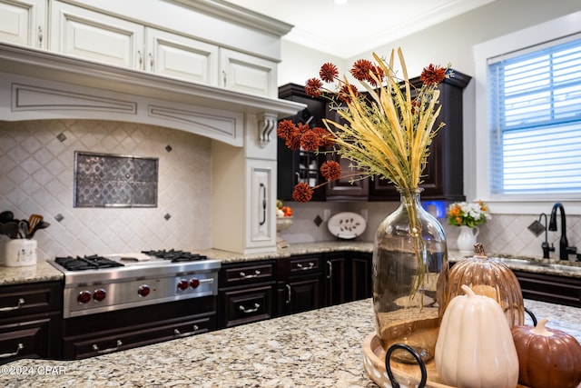 kitchen with ornamental molding, stainless steel gas stovetop, white cabinets, and tasteful backsplash