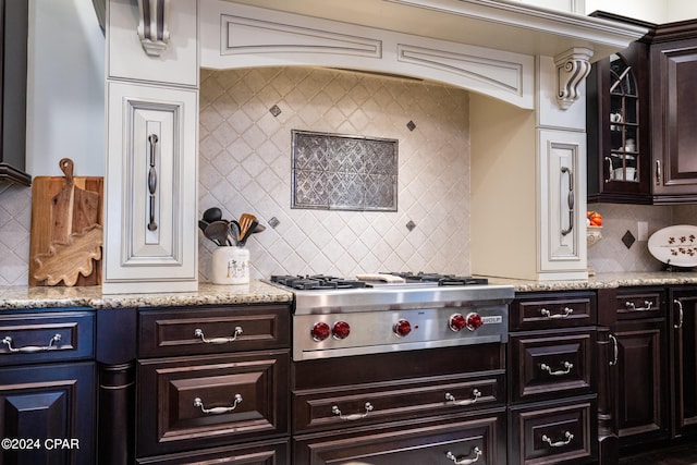 kitchen featuring light stone countertops, stainless steel gas cooktop, dark brown cabinets, and backsplash