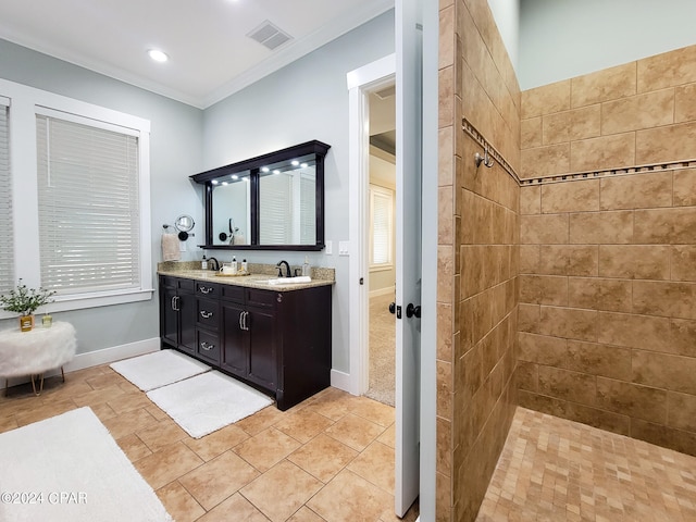 bathroom with vanity, ornamental molding, tiled shower, and tile patterned floors