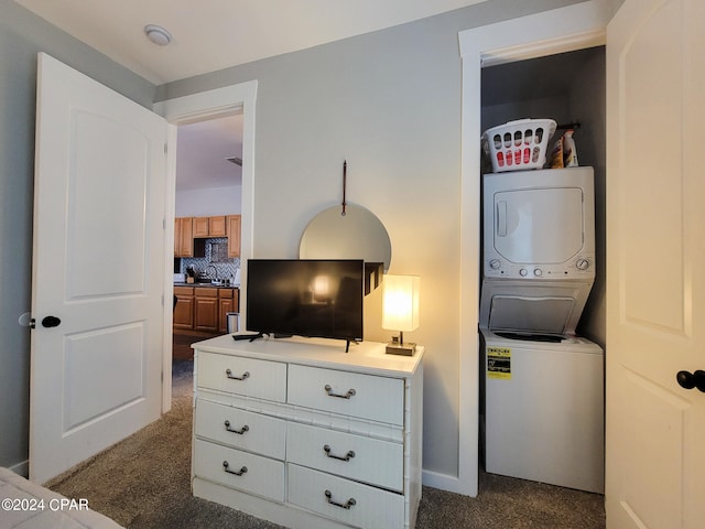 bedroom featuring stacked washer / dryer and dark colored carpet