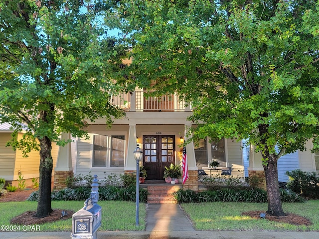 view of front of property featuring a front yard and a balcony