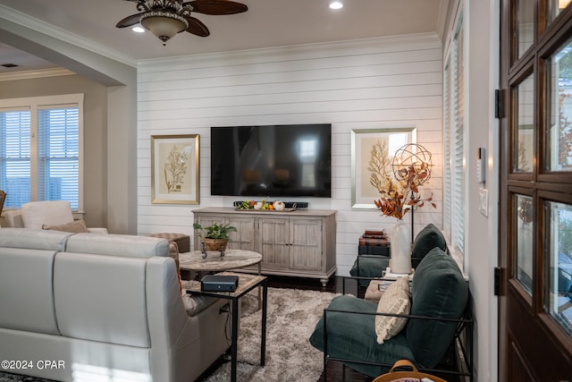 living room with crown molding, wooden walls, and ceiling fan