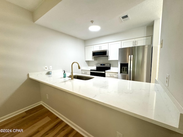 kitchen with kitchen peninsula, sink, white cabinets, appliances with stainless steel finishes, and dark hardwood / wood-style flooring