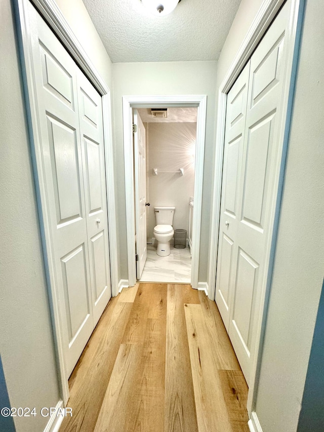hallway featuring a textured ceiling and light wood-type flooring