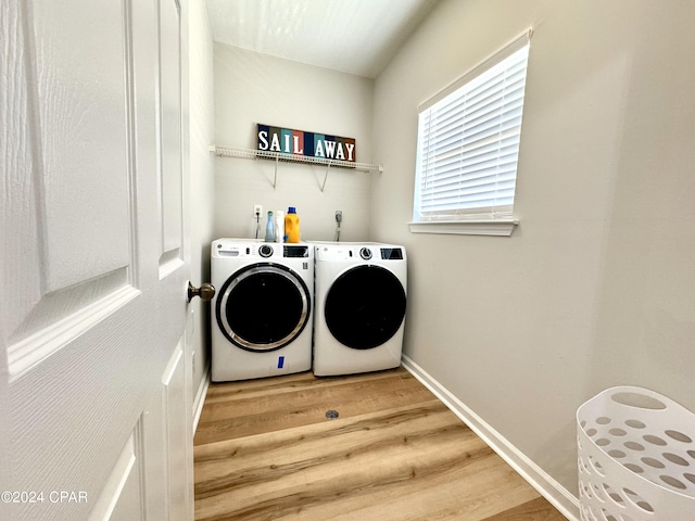 clothes washing area with hardwood / wood-style floors and washer and dryer
