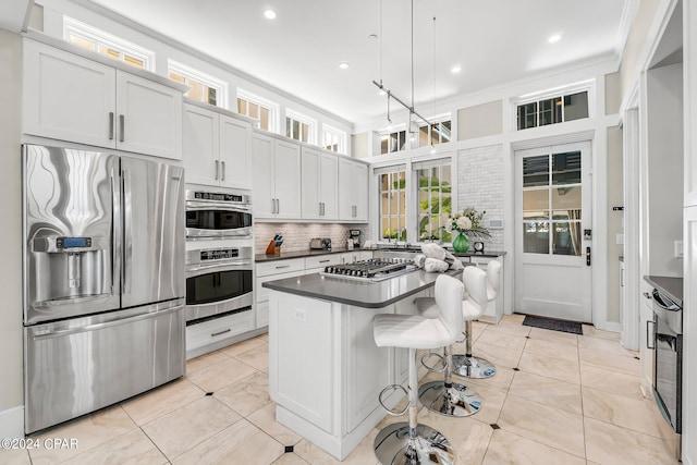 kitchen featuring a center island, stainless steel appliances, decorative light fixtures, white cabinets, and ornamental molding