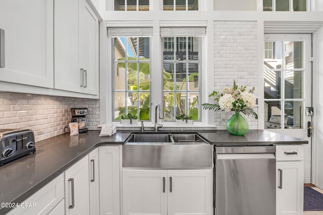 kitchen featuring decorative backsplash, white cabinetry, dishwasher, and sink